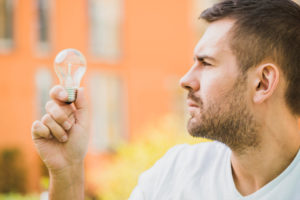 side view of man looking at light bulb